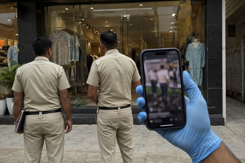 Police officers escorting a man inside a clothing showroom during an investigation